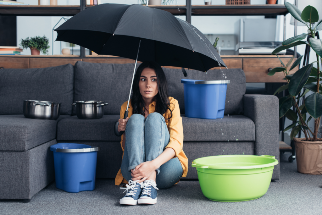 Een vrouw zit verward met een paraplu in huis tegen de lekkage